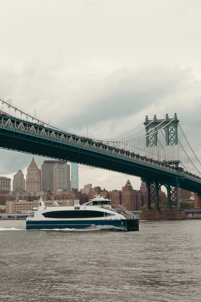 Modern yacht on Hudson river under Manhattan bridge and cloudy sky in New York City — Fotografia de Stock