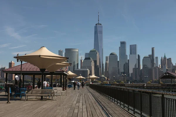 NEW YORK, USA - 13. OKTOBER 2022: Menschen gehen auf einem Damm mit Blick auf Manhattan-Wolkenkratzer — Stockfoto
