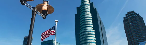 Vue à angle bas de lanterne et drapeau des Etats-Unis près des gratte-ciel sous le ciel bleu à New York, bannière — Photo de stock