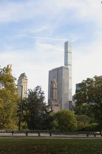 Rascacielos modernos cerca del parque urbano bajo el cielo azul y nublado de la ciudad de Nueva York - foto de stock