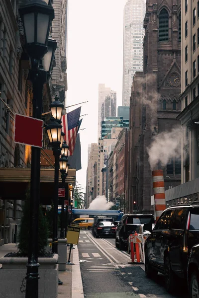 NEW YORK, États-Unis - 13 OCTOBRE 2022 : rue étroite avec voitures et lanternes près des drapeaux des États-Unis à Manhattan — Photo de stock