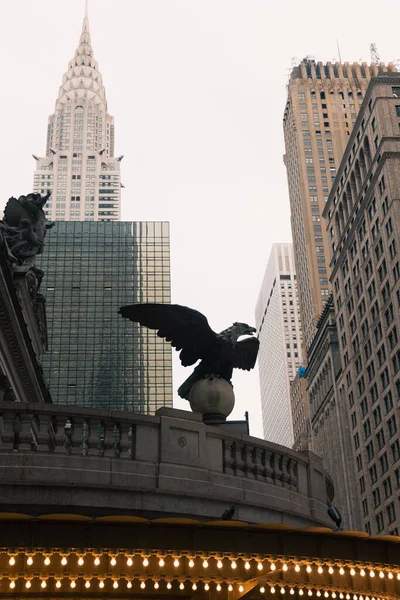 Luminous garland and eagle statue on New York Grand Central Terminal near skyscrapers and Chrysler building on background — Fotografia de Stock