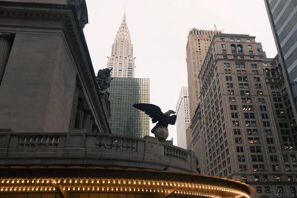 Eagle statue and luminous garland on facade of Grand Central Terminal with Chrysler building on background in New York City — Fotografia de Stock