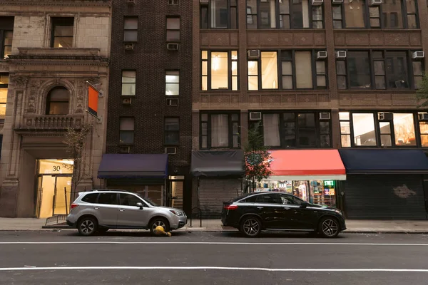 NEW YORK, USA - OCTOBER 13, 2022: cars near buildings with shops on road of urban street — Fotografia de Stock