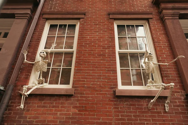 Baixo ângulo de visão de esqueletos assustadores na janela da casa de tijolos em Nova York — Fotografia de Stock