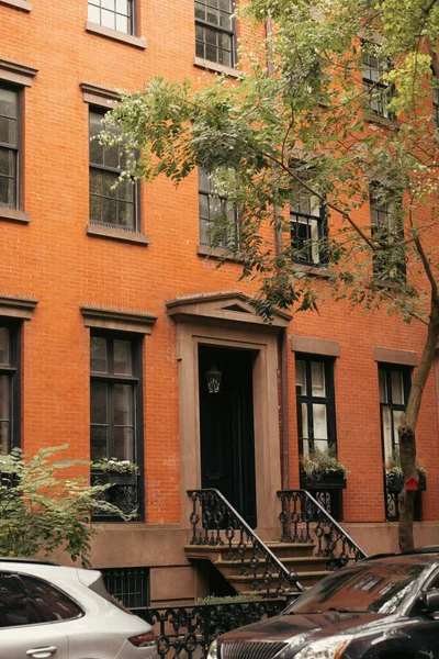 Red brick building near cars and trees in Brooklyn Heights district in New York City - foto de stock