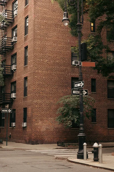 Ponteiros na lanterna perto de estrada e tijolo edifício na rua em Nova York — Fotografia de Stock