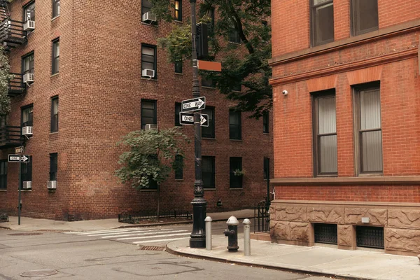 Указатели между кирпичными зданиями на улице в Нью-Йорке — стоковое фото