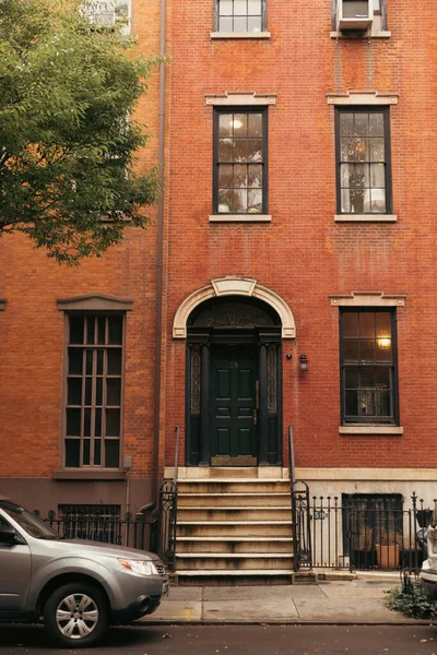 Car near entrance of brick house on street of brooklyn heights in New York City - foto de stock