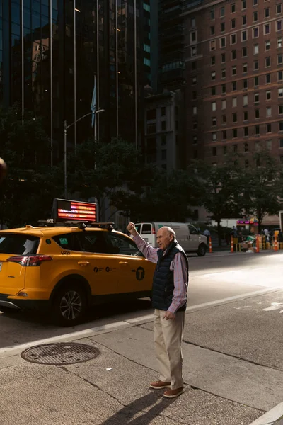 NEW YORK, USA - OCTOBER 11, 2022: Man catching taxi on urban street in Manhattan — стокове фото