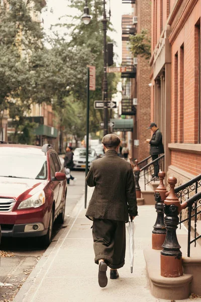 NUEVA YORK, EE.UU. - 11 de octubre de 2022: Hombre sosteniendo paraguas mientras camina por la calle urbana de Manhattan - foto de stock