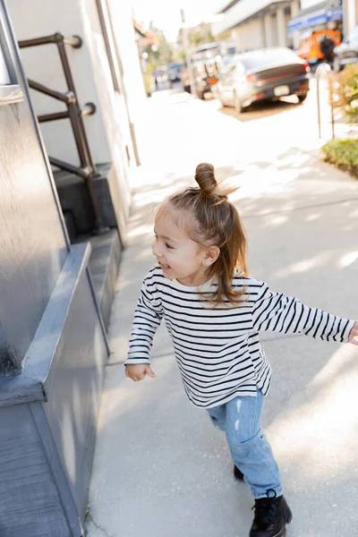 Cheerful toddler child in long sleeve shirt and blue jeans walking on street in Miami — Stock Photo
