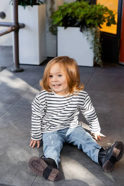 Niño feliz niño sentado en el porche en el patio trasero al lado de la casa en Miami - foto de stock