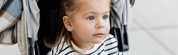 Toddler kid in striped long sleeve shirt sitting in baby stroller, banner — Stock Photo