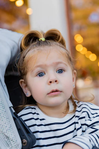 Portrait de tout-petit enfant en chemise à manches longues rayée assis dans une poussette — Photo de stock