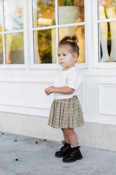 Full length of toddler girl in skirt and white t-shirt standing near house — Stock Photo