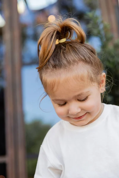 Ritratto di bambina sorridente in t-shirt bianca sorridente e guardando in basso — Foto stock