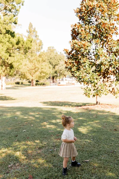 Comprimento total da menina na saia e camiseta branca em pé no parque — Fotografia de Stock