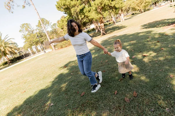Alegre mãe e criança de mãos dadas enquanto brincam juntos no verde Miami park — Fotografia de Stock