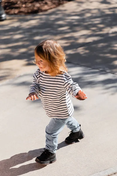 Vista ad alto angolo del bambino in camicia a maniche lunghe a righe e jeans blu che camminano per strada a Miami — Foto stock