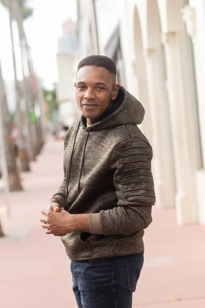 Веселий афроамериканський чоловік в светрі дивиться на камеру на міській вулиці — стокове фото