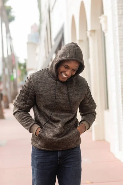 Happy african american man in hoodie walking with hands in pockets in Miami — Stock Photo