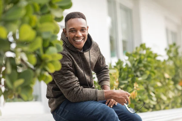 Happy african american man in hoodie and jeans holding sunglasses in Miami — Stock Photo
