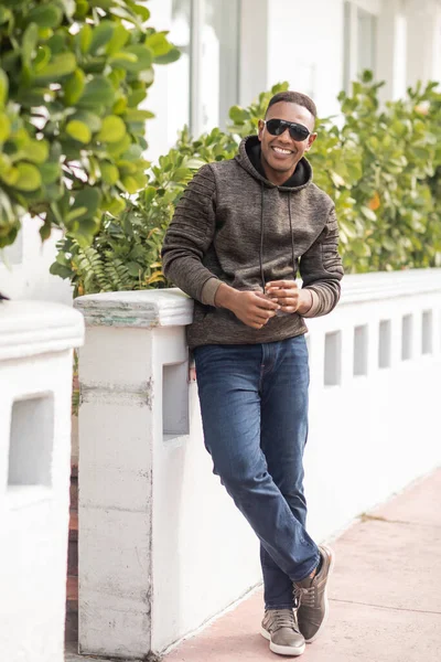 Piena lunghezza di gioioso uomo africano americano in felpa con cappuccio e occhiali da sole alla moda in piedi all'aperto — Foto stock