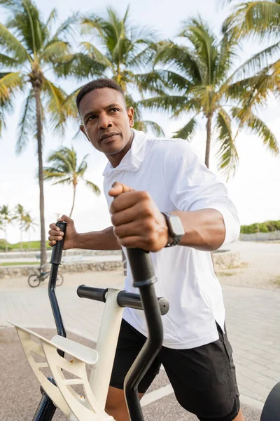 Sportive african american man exercising on cross trainer in outdoor gym — Stock Photo