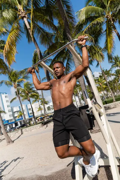 Без сорочки афроамериканський спортсмен робить тягнути злети у відкритому тренажерному залі на пляжі Маямі — стокове фото