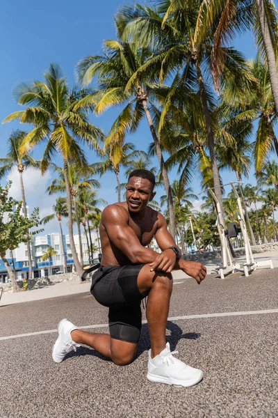 Sportivo afroamericano senza maglietta che si riposa dopo l'allenamento accanto alle palme a Miami — Foto stock