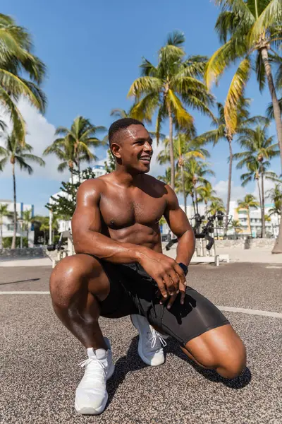 Felice sportivo afroamericano in pantaloncini corti e scarpe da ginnastica sorridente dopo l'allenamento a Miami Beach — Foto stock