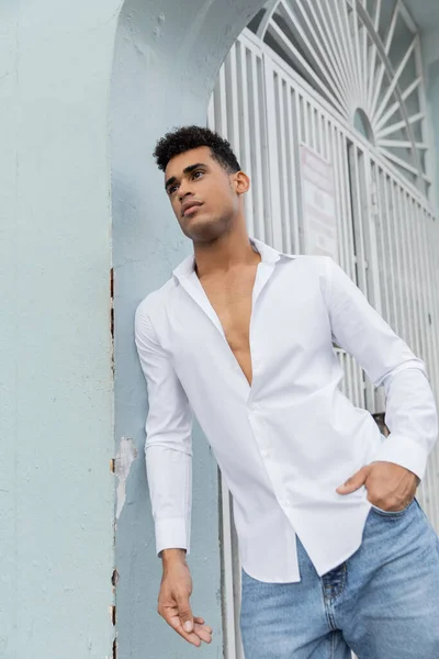 Homme cubain beau et bouclé en chemise élégante et jeans bleus posant dans la rue à Miami — Photo de stock