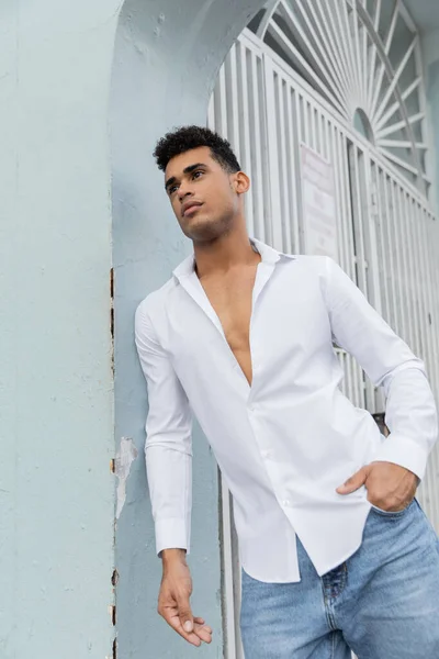 Handsome and curly cuban man in stylish shirt and blue jeans posing on street in Miami — Stock Photo
