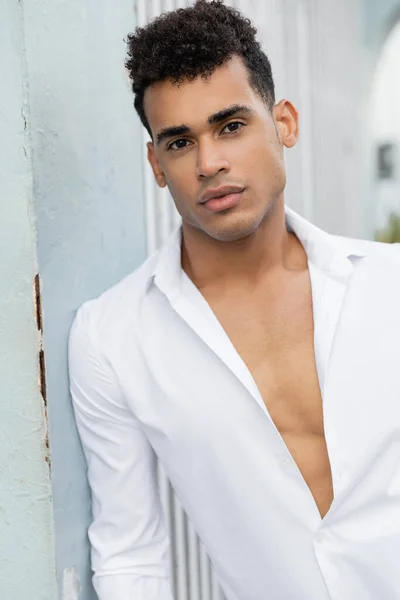 Porträt eines jungen, lockigen kubanischen Reisenden im weißen Hemd, der auf der Straße in Miami in die Kamera blickt — Stockfoto