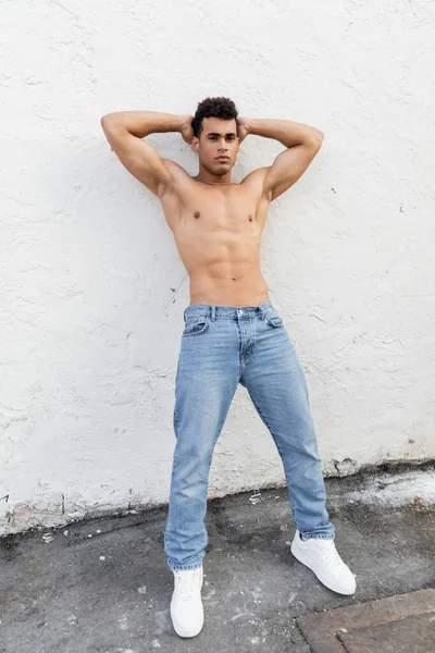 Piena lunghezza di atletico uomo cubano in blue jeans posa vicino edificio in strada a Miami — Foto stock