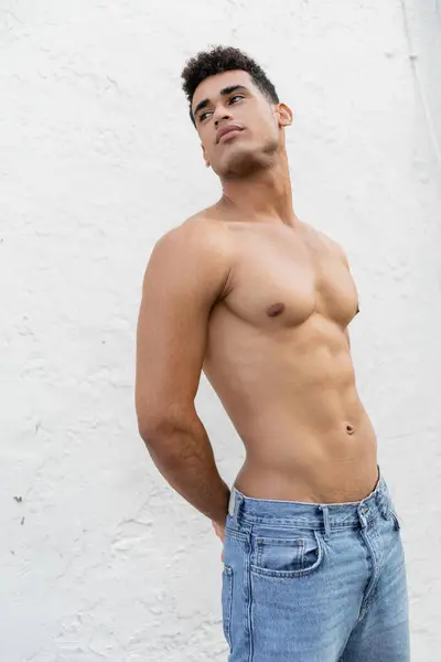 Joven y sexy hombre cubano con cuerpo atlético de pie cerca de la pared en Miami, al sur de la playa - foto de stock