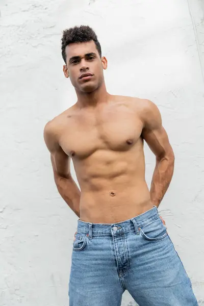 Cubain homme avec corps athlétique en jeans regardant caméra près de bâtiment sur à Miami, musclé — Photo de stock