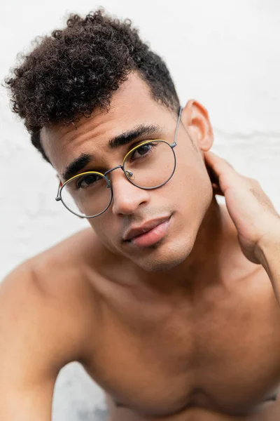 Portrait de jeune homme cubain en lunettes rondes touchant le cou et regardant la caméra — Photo de stock