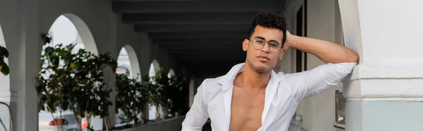 Jeune homme cubain sexy avec des lunettes élégantes et chemise blanche regardant la caméra à Miami, bannière — Photo de stock