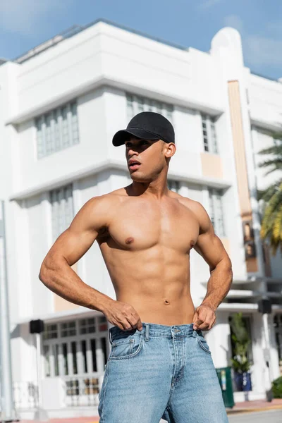 Bel homme cubain avec un corps athlétique dans la casquette de baseball dans la rue urbaine de Miami, pendant l'été — Photo de stock
