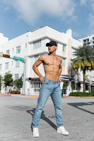 Hombre cubano guapo con cuerpo atlético en gorra de béisbol en la calle urbana de Miami, verano - foto de stock