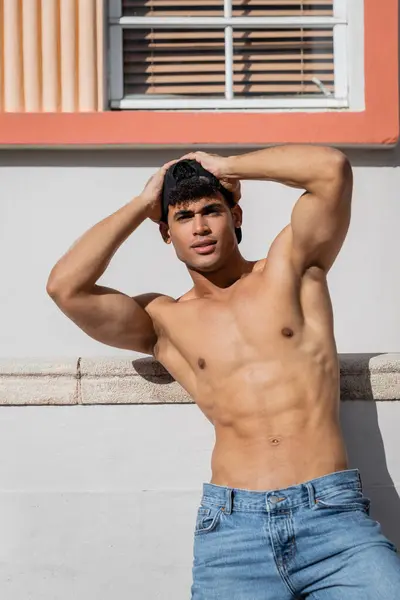 Sem camisa cubano homem com sexy corpo em boné de beisebol e jeans de pé na rua em Miami — Fotografia de Stock