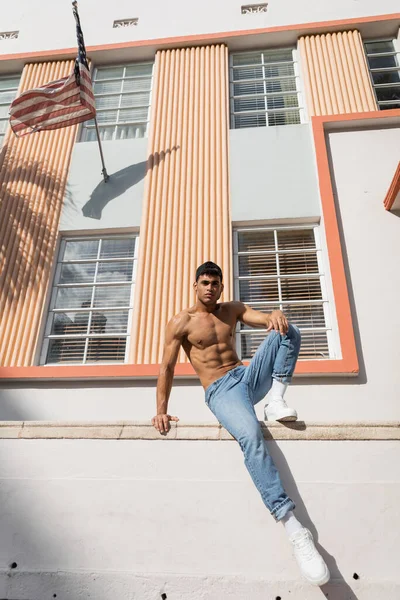 Homem cubano com corpo muscular posando em boné de beisebol e jeans na rua em Miami — Fotografia de Stock