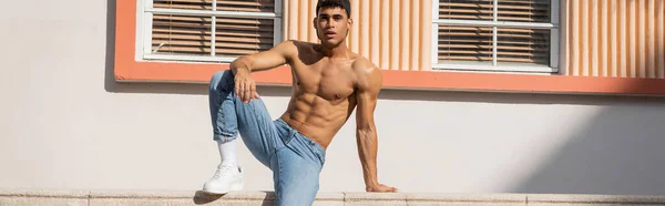 Cuban man with muscular body posing in baseball cap and jeans on street in Miami in summer, banner — Stock Photo