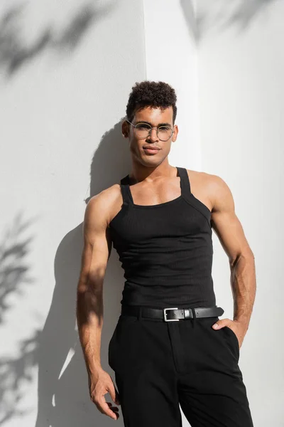 Портрет модного мускулистого кубинца в очках и черной футболке без рукавов, позирующей у стены — стоковое фото
