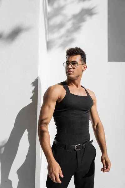 Jeune homme cubain à lunettes debout près du bâtiment avec ombre sur la rue à Miami, plage sud — Photo de stock