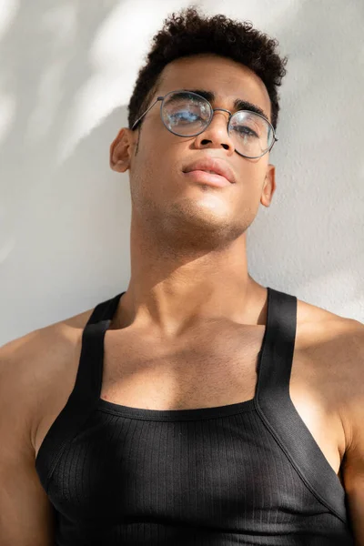 Portrait of trendy and muscular cuban man in eyeglasses and sleeveless t-shirt looking at camera — Stock Photo