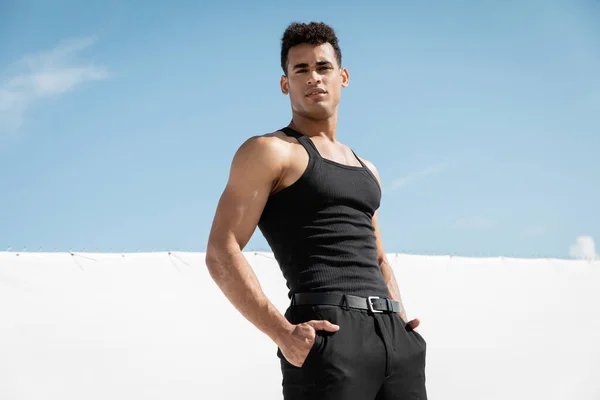 Schöner junger kubanischer Mann in schwarzer Kleidung posiert mit Händen in Taschen in Miami, Südstrand — Stockfoto