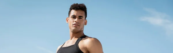 Muscoloso giovane cubano in abito nero in posa con cielo sullo sfondo, striscione — Foto stock